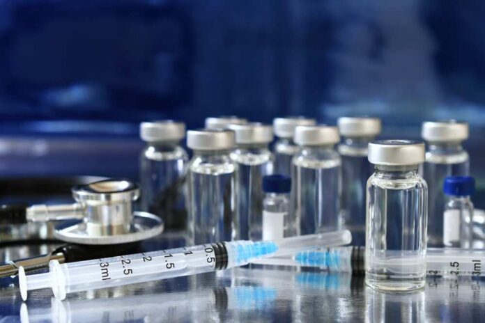 Medical vials and syringes arranged on a reflective surface