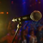 Close-up of a microphone in front of a blurred audience at a concert