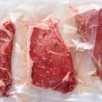 Three vacuum sealed steaks on a white surface