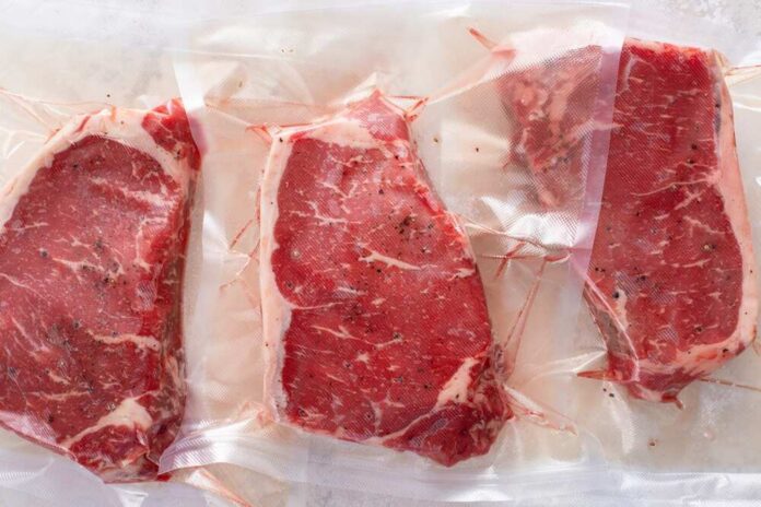 Three vacuum sealed steaks on a white surface