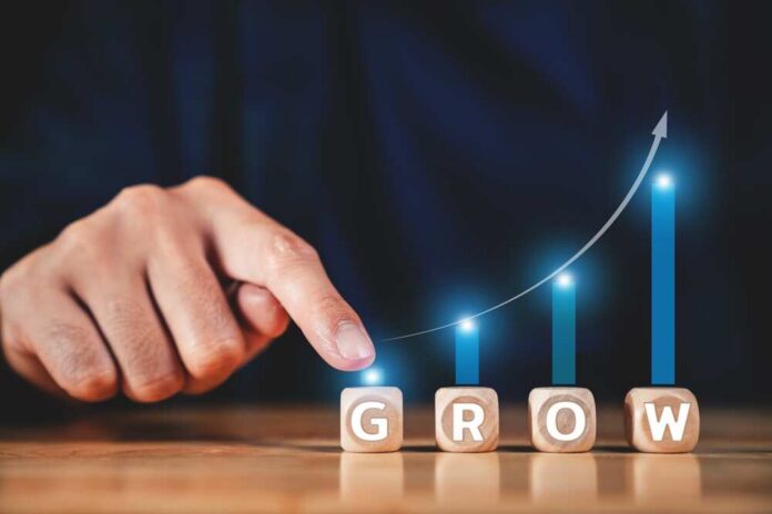 A hand pointing at wooden blocks spelling 'GROW' with a rising graph in the background