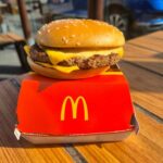 McDonald’s Big Arch Shocker: Crushes Big Mac? A cheeseburger from McDonald's placed on a red box on a wooden table