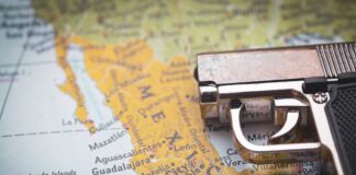 A close-up of a gun resting on a map of Mexico