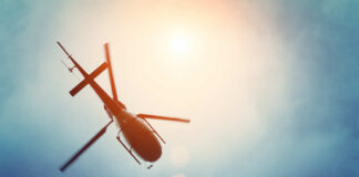 A helicopter flying against a bright sky