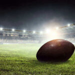 Football on field in illuminated stadium at night.
