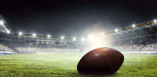 Football on field in illuminated stadium at night.