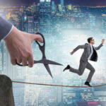 A businessman running on a tightrope with a giant hand holding scissors above him