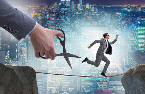 A businessman running on a tightrope with a giant hand holding scissors above him