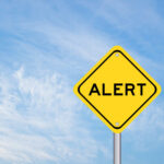 Yellow alert sign against a blue sky