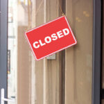 A red 'CLOSED' sign hanging on a storefront door