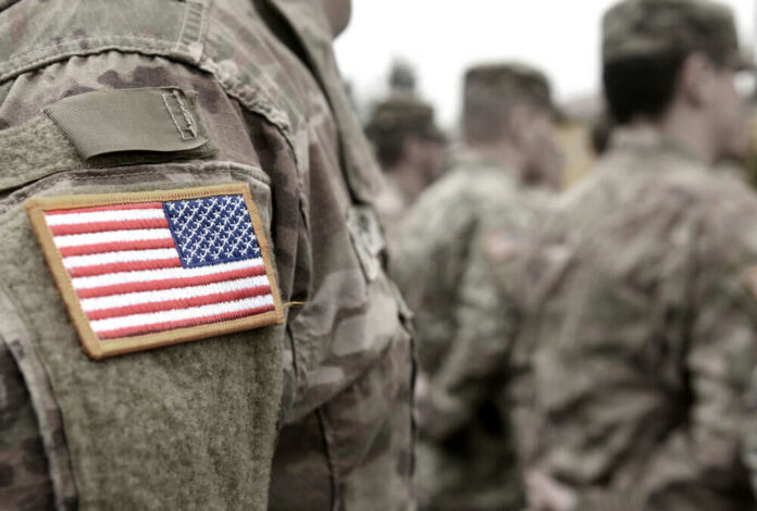 shutterstock_1836976885.jpg Soldiers in camouflage uniforms with American flag patches.