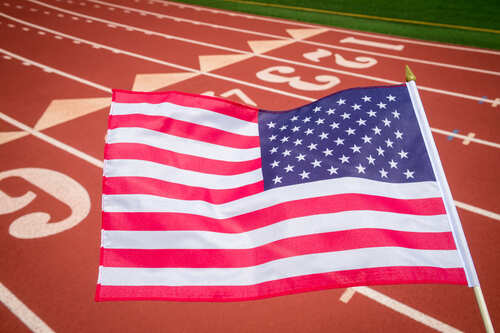 shutterstock_2004087047 (1).jpg American flag waving in front of a running track