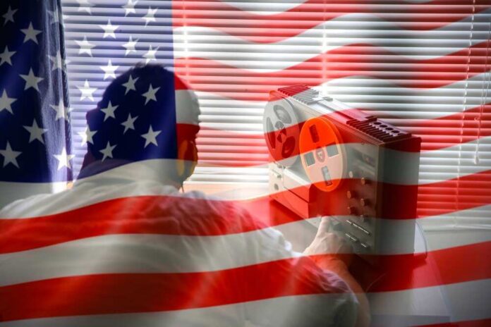 shutterstock_2145579929.jpg Person using a vintage tape recorder with an American flag overlay