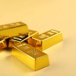 Several gold bars stacked on a golden surface