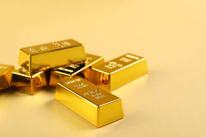 Several gold bars stacked on a golden surface