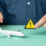 22 Dead: Plane Crash Disaster Update A person holding a warning sign next to a model airplane