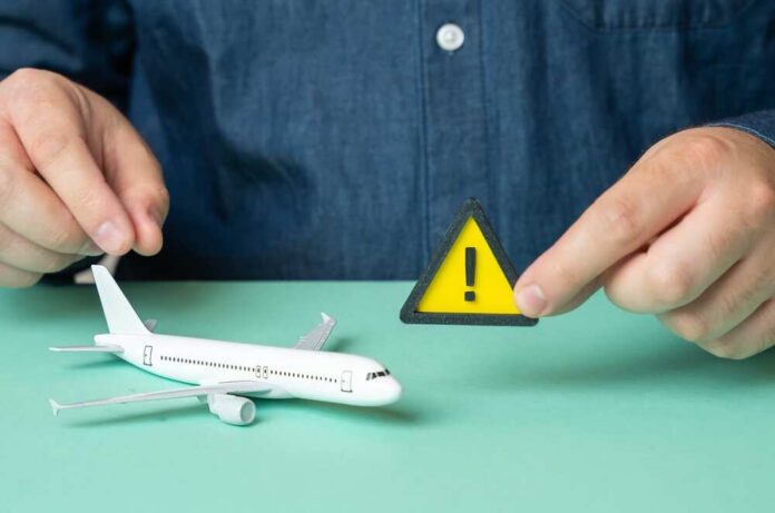 A person holding a warning sign next to a model airplane