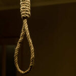 A close-up of a noose hanging in a dimly lit room