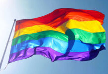 Rainbow flag waving against clear blue sky