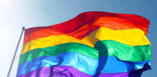 Rainbow flag waving against clear blue sky
