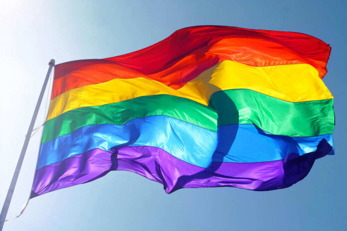 Rainbow flag waving against clear blue sky