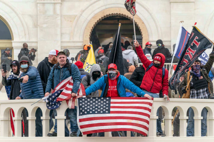 Group of people with flags outside a building balcony.
