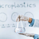 Scientist holding a flask containing water with microplastics in a laboratory setting