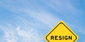 A yellow warning sign with the word 'RESIGN' against a blue sky