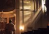 Surprising Restraint: American Pope’s Easter Message A clergy member standing in a church with light streaming through windows