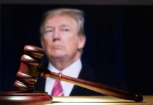 Gavel in foreground with blurry man in background.