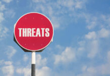 Red sign with the word threats against sky