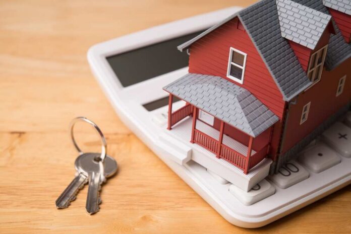 A miniature red house on a calculator with keys nearby