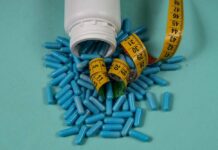 Spilled blue capsules and a measuring tape on a turquoise background