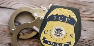 ICE officer badge next to handcuffs on a wooden surface