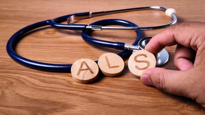 A hand holding wooden letters 'A', 'L', and 'S' next to a stethoscope on a wooden surface