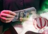 A person holding a stack of US hundred-dollar bills in front of the Iranian flag