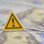 War Drains $25B — Congress ERUPTS A warning sign placed on top of U.S. dollar bills