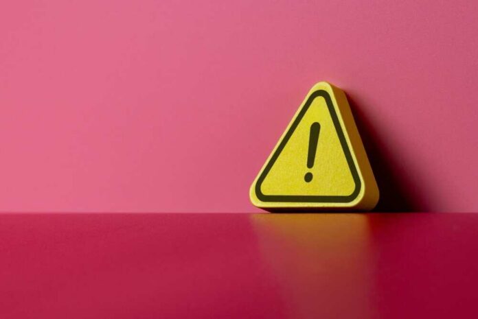 Yellow triangular warning sign on a pink background