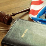 Court UNLEASHES Ten Commandments Gavel, Holy Bible, and American flag on a desk.