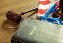 Gavel, Holy Bible, and American flag on a desk.