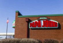 Exterior view of a Papa John's pizza restaurant with a flag in the background