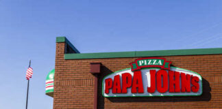 Exterior view of a Papa John's pizza restaurant with a flag in the background