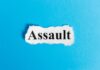 The word 'Assault' printed on torn paper against a blue background