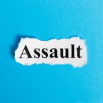 The word 'Assault' printed on torn paper against a blue background
