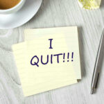 Note with I QUIT near coffee, pen, paper ball.