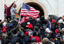 Controversy: JAN 6 Cops Sue DOJ Crowd storming a building, waving an American flag.
