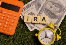 Calculator, dollar bills, and letter tiles spelling 'IRA' on grass