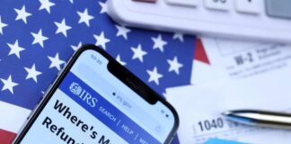 Smartphone displaying IRS website with tax documents and American flag in the background