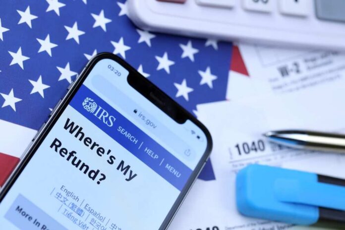 Smartphone displaying IRS website with tax documents and American flag in the background