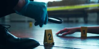 A detective examining evidence at a crime scene with markers on the floor